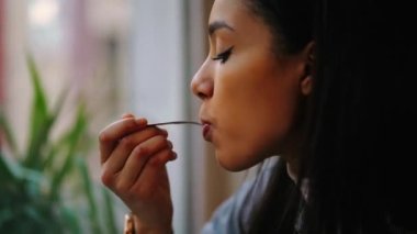 Kadın kahvecide otururken kahve içiyor.