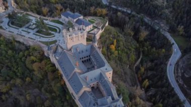 Sonbaharda İspanya 'nın Avila kentinde, yolun kenarındaki tepedeki yemyeşil ağaçların arasında bulunan Segovia' lı Alcazar 'ın insansız hava aracı görüntüsünden.