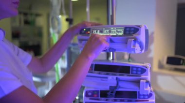 Back view of crop unrecognizable woman in white medical scrub is focusing on screen and adjusting settings of contemporary digital medical equipment in hospital