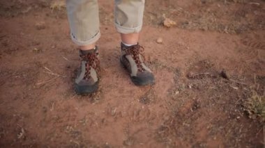 Kırpılmış, tanınmayan, yürüyüş ayakkabılı kadın gezgin çöl arazisinde kuru zeminde yürüyordu.