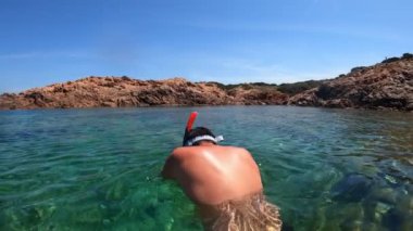Yüzme şortu ve şnorkelle yüzen bir adam Sardunya adasında suyun altında yüzer.