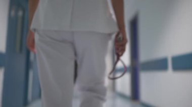  Nöbet bitiminden sonra kliniğin koridorunda yürüyen beyaz üniformalı çocuk doktorunun arka görüntüsü.