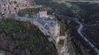 Sonbaharda İspanya 'nın Avila kentinde, yolun kenarındaki tepedeki yemyeşil ağaçların arasında bulunan Segovia' lı Alcazar 'ın insansız hava aracı görüntüsünden.
