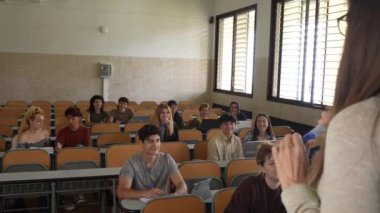 Anonim bir öğretmenin konferans salonunda oturan bir grup öğrenciye ders vermesinden.