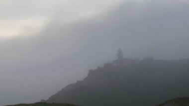 Punta Del Torco Del Fuera Deniz Feneri 'nin sisli bir sabahta Suances, Cantabria, İspanya' da, deniz kenarındaki çimenli kayalıklarda yer alan statik görüntüsü.