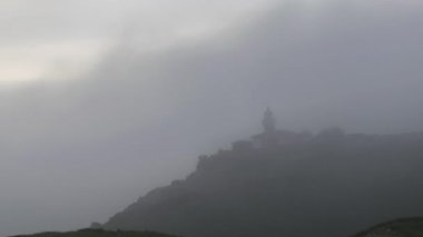 Punta Del Torco Del Fuera Deniz Feneri 'nin sisli bir sabahta Suances, Cantabria, İspanya' da, deniz kenarındaki çimenli kayalıklarda yer alan statik görüntüsü.