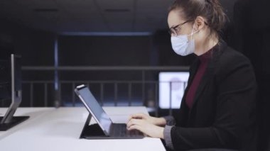 İş kadını uzmanının masada oturup, iş yerinde çalışırken boş beyaz ekranla klavyeye yazışının yan görüntüsü