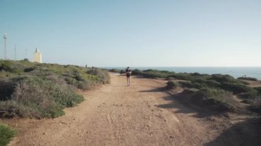 Gün batımında dağlarda spor kıyafetleri içinde koşan genç bir bayan koşucu. Deniz manzaralı. 