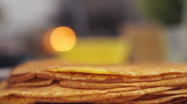 Anonim kadın aşçı bir spatulayla tavadan krepi alıp başka bir gözlemenin üstüne koyuyor.