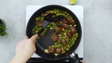 Portatif fırında tavada kızartılan meçhul kadın köfteleri, yeşil fasulyeler ve fıstıkların gerçek zamanlı görüntüsü.