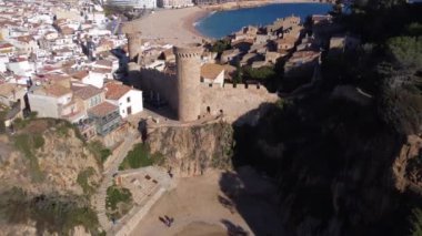 İspanya 'da gün ışığında dalgalı deniz kıyısında yerleşim evleri bulunan yaşlı bir kasabanın hava manzarası.