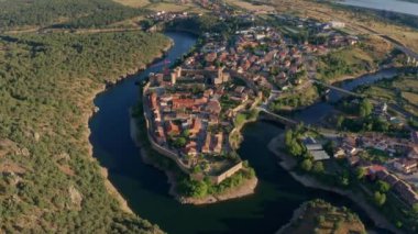 Buitrago del Lozoya 'nın dolambaçlı nehir ve otlaklarla çevrili eski bir kasabasının insansız hava aracı görüntüsü