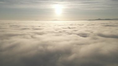 Akşam vakti renkli günbatımında beyaz, kalın ve yumuşak bulutların üzerinde yavaş çekim hava manzarası