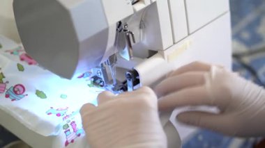 Arka planda dikiş makinesiyle çalışan kadın