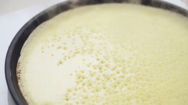 Anonim biri mutfakta bir tavada krep hamuru çeviriyor.