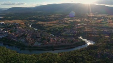 Buitrago del Lozoya 'nın dolambaçlı nehir ve otlaklarla çevrili eski bir kasabasının insansız hava aracı görüntüsü