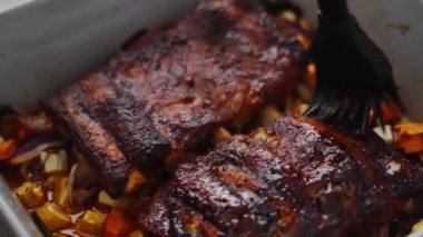 Evde öğle yemeği hazırlıkları sırasında pirzola ve sebzeyle kızartılmış domuz pirzolasına tuz dökmek için fırça kullanan biri.