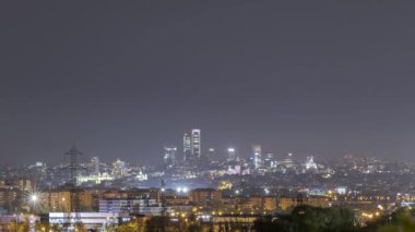 Madrid 'in ışıldayan dört kulesinin anlık statik görüntüleri İspanya' da sağanak yağış eşliğinde karanlık akşam gökyüzünün altında aydınlık caddelerde yer alıyor.