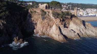 İspanya 'da gün ışığında dalgalı deniz kıyısında yerleşim evleri bulunan yaşlı bir kasabanın hava manzarası.