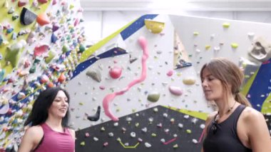 Spor kıyafetleri içinde, elleri tebeşirle kaplanmış sporcu kadınların tırmanmadan önce birbirlerine beşlik çakışları.