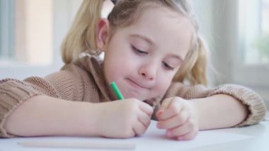 Küçük kız kağıda resim çiziyor.