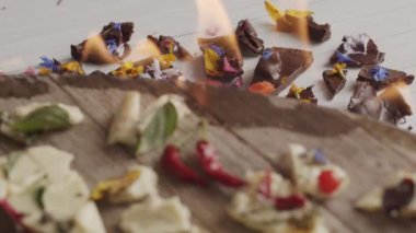 Çiçek ve yapraklarla kaplı vejetaryen margarinin üst görüntüsü ateş alevleriyle çevrili.