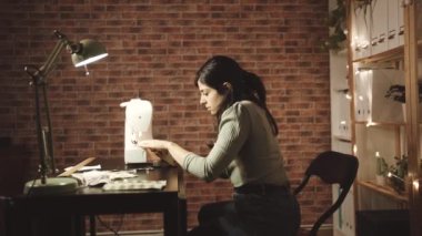 Arka planda dikiş makinesiyle çalışan kadın
