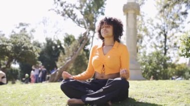 Nilüfer çiçekli poz verip parkta yoga yaparken nefes alan barışçıl Afro-Amerikan kadınlarından oluşan el kamerasıyla çekilmiş bir fotoğraf.