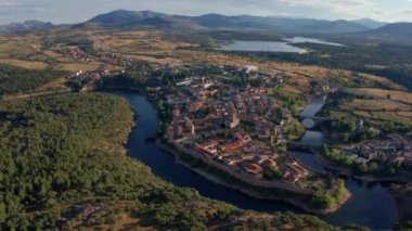 Buitrago del Lozoya 'nın dolambaçlı nehir ve otlaklarla çevrili eski bir kasabasının insansız hava aracı görüntüsü
