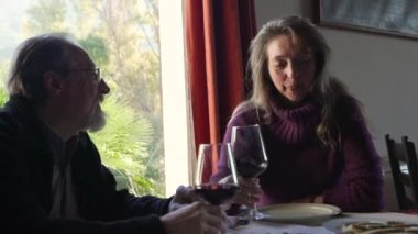 Restoranda yemek ve şarapla yemek yerken yaşlı çift konuşuyor. Pencereden doğanın manzarası çok güzel.
