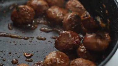 Köfte çeviren, elektrikli fırında kızartan, mutfakta tezgahta yemek pişiren isimsiz bir adam.