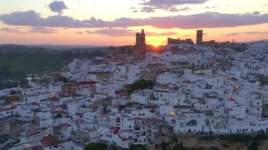 İspanya, Endülüs 'te bulutlu gün batımına karşı kayalıklarda bulunan Arcos de la Frontera kasabasının nefes kesici insansız hava aracı manzarası