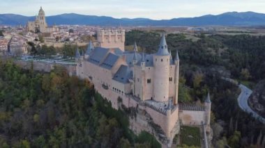 Sonbahar akşamı İspanya 'nın Avila kentinde, yol kenarındaki yemyeşil ağaçların arasında bulunan Segovia' lı Alcazar 'ın insansız hava aracının yukarıdan görünüşü
