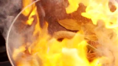 Mutfakta deniz ürünleri yemeği hazırlarken elinde maşayla tavada karides pişirirken yakın plan fotoğrafı.