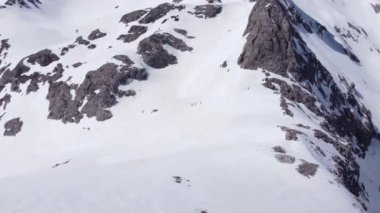İspanya 'nın kışın doğasında, Picos de Europa dağının karlı yamacında gezinen tanınmayan bir grup insanın görüntüsü.