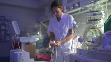 Beyaz önlüklü kadının yan görüntüsü ekrana odaklanıyor ve hastanedeki çağdaş dijital tıbbi ekipman ayarlarını ayarlıyor