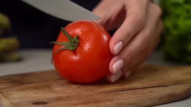 Kadın kırmızı domatesi bıçakla kesiyor. 