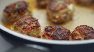 Köfte çeviren, elektrikli fırında kızartan, mutfakta tezgahta yemek pişiren isimsiz bir adam.