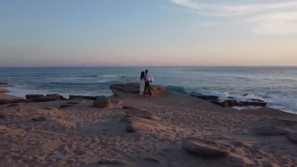 在日落时分 穿着婚纱的新婚夫妇在海滨共度浪漫时光 — 图库视频影像