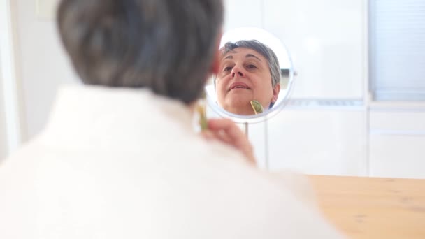 Mujer Mediana Edad Albornoz Mirando Espejo Masajeando Cara Con Rodillo — Vídeos de Stock