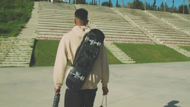 Tracking Shot Ragazzo Afroamericano Con Cappuccio Che Trasporta Skateboard Sul — Video Stock
