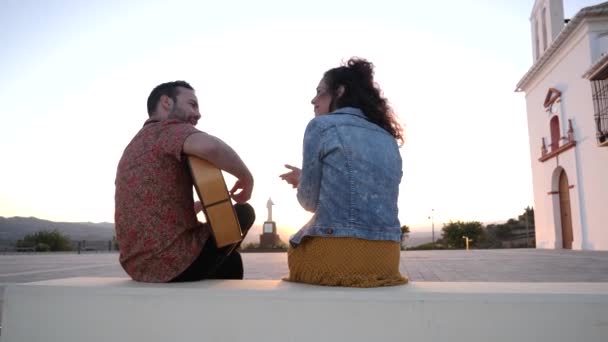 ストリートのアコースティックギターで歌う男性ミュージシャンに耳を傾けながら 匿名の女性のリアルタイムのバックビュー — ストック動画