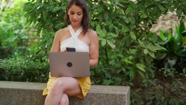 注意深い自己雇用された女性はスマートフォンを話し 夏の庭でラップトップと座っている間プロジェクトで働きます — ストック動画