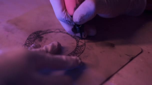 从上到下 穿着乳胶手套的收割者坐在桌旁 在昏暗的工作室里练习 在皮革上画纹身 — 图库视频影像