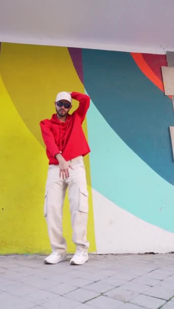 在城市街道上五彩斑斓的城墙附近的人行道上 身穿时髦服装的体态丰满的男性舞蹈演员的静态镜头 — 图库视频影像