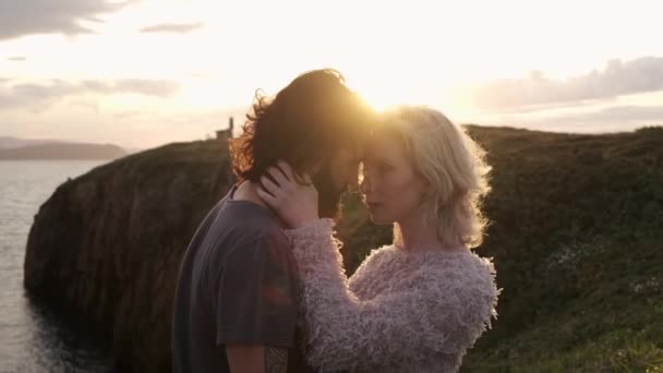 お互いに抱擁し スペインのアヴィレスの自然の中でロマンチックな日付の間に日没の空に対して額に触れる男女の側面の眺め — ストック動画