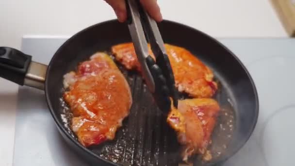在厨房做饭的过程中 匿名厨师用钳子搅拌平底锅中美味的软骨素腌制油炸食品时的高角度特写 — 图库视频影像