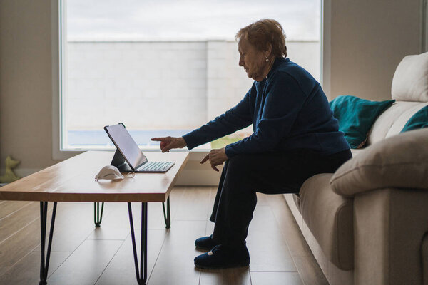 Old woman communicating with daughter on video chat on laptop