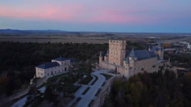 Yukarıdan, İspanya 'nın Avila şehrinde sonbahar akşamı yol kenarındaki yemyeşil ağaçların arasında bulunan Segovia' lı Alcazar 'ın insansız hava aracı görüntüsü.