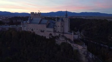 Sonbahar akşamı İspanya 'nın Avila kentinde, yol kenarındaki yemyeşil ağaçların arasında bulunan Segovia' lı Alcazar 'ın insansız hava aracının yukarıdan görünüşü